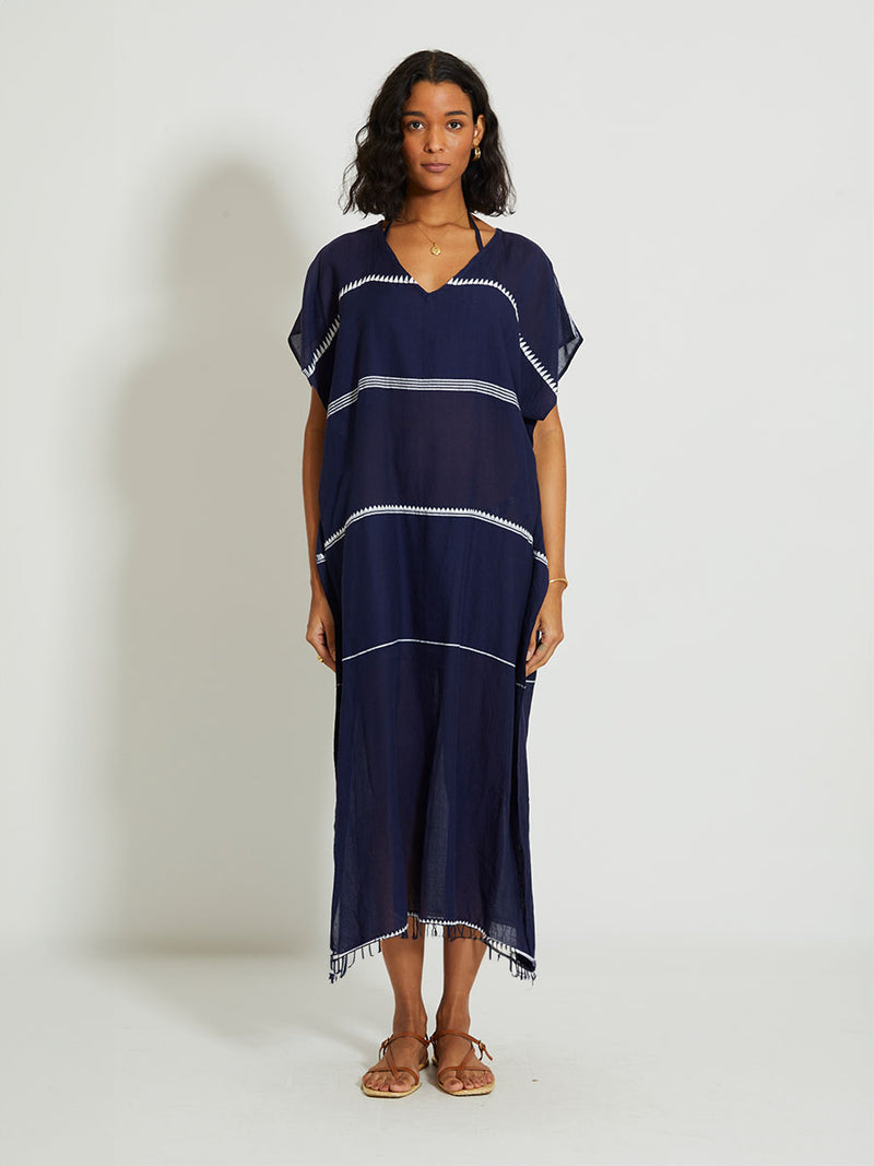 Woman standing wearing the Nunu classic caftan in navy blue featuring white stripes and graphic lines.