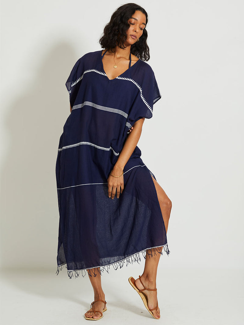 Woman standing wearing the Nunu classic caftan in navy blue featuring white stripes and graphic lines.