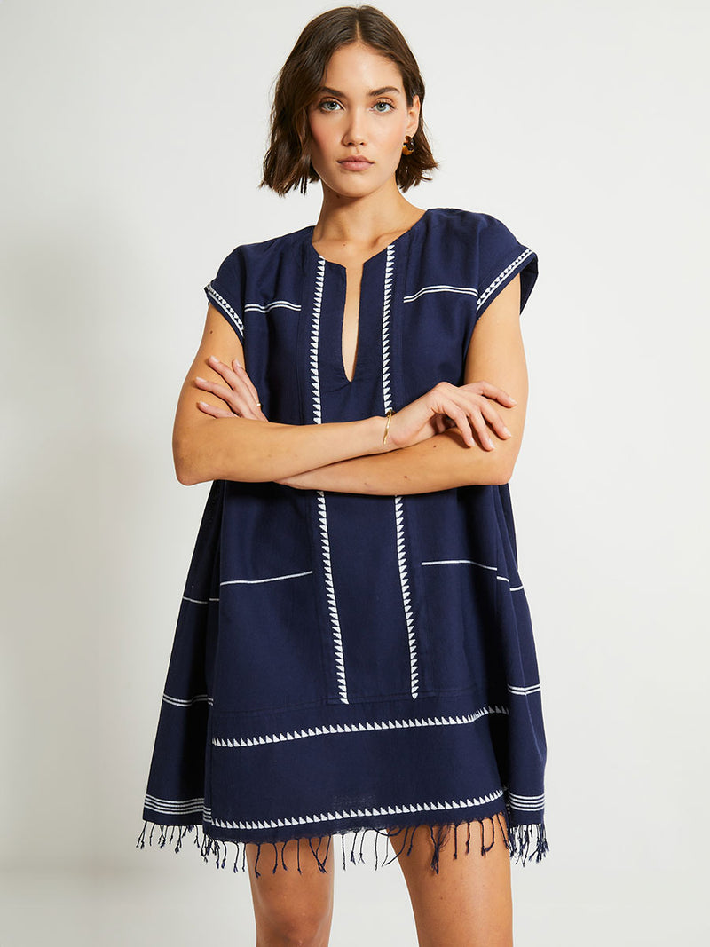 Woman Standing Wearing lemlem ELINA Caftan featuring  delicate white Tibeb bands on a rich navy background