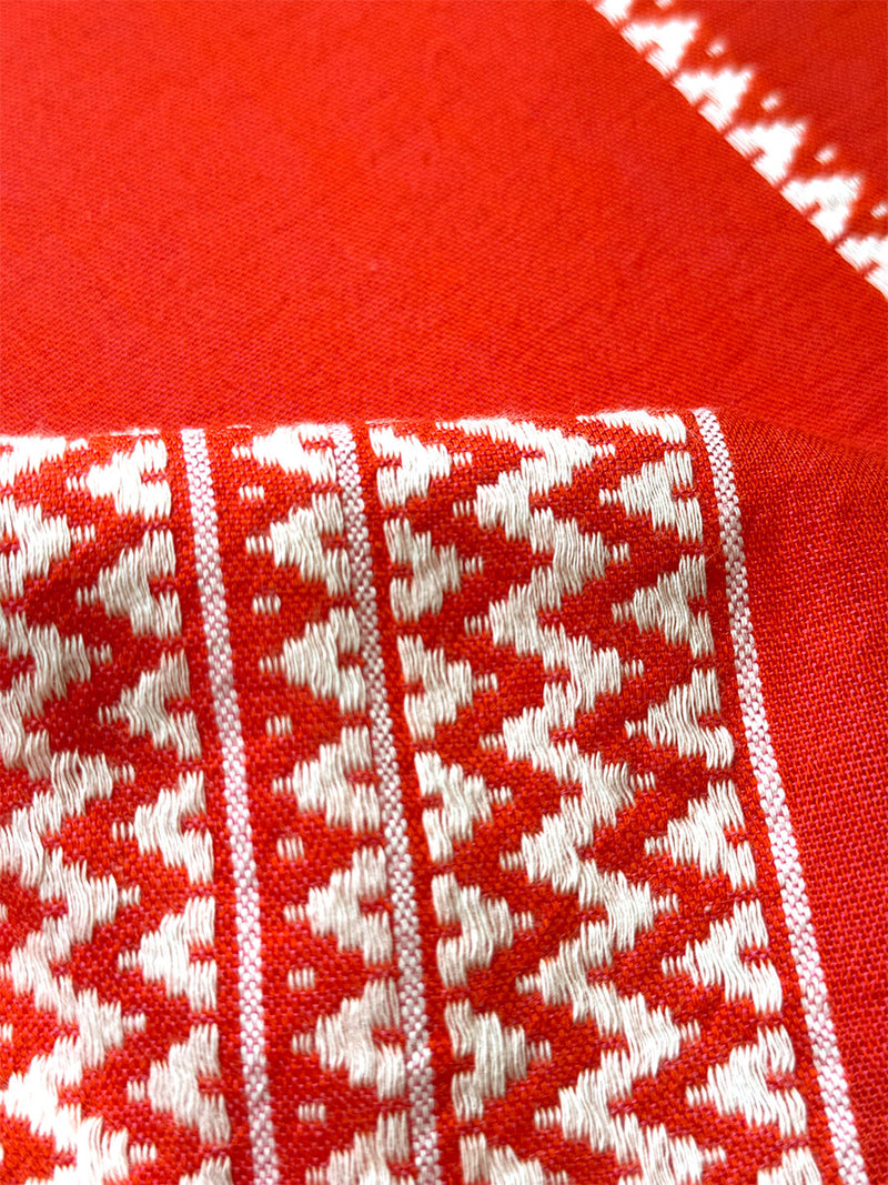 Close up on lemlem Tenesa Red Fabric featuring an intricate Tibeb pattern in rich red and vanilla colors