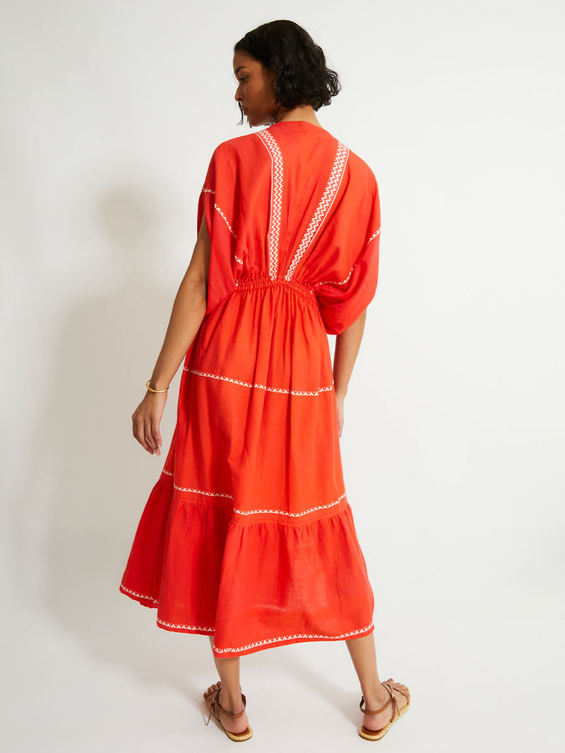 Back of a Woman Standing Wearing lemlem LELISA Dress featruing an intricate Tibeb pattern in rich red and vanilla colors