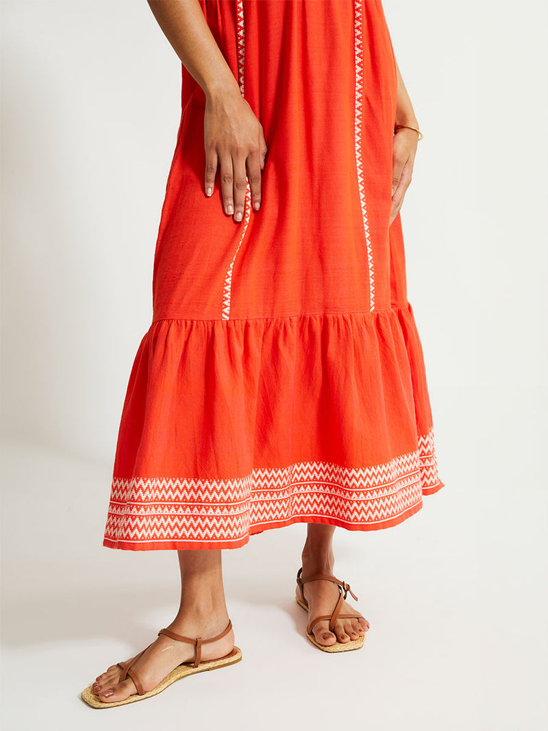 Close up on Woman's Legs Standing Wearing lemlem LELISA Dress featuring an intricate Tibeb pattern in rich red and vanilla colors