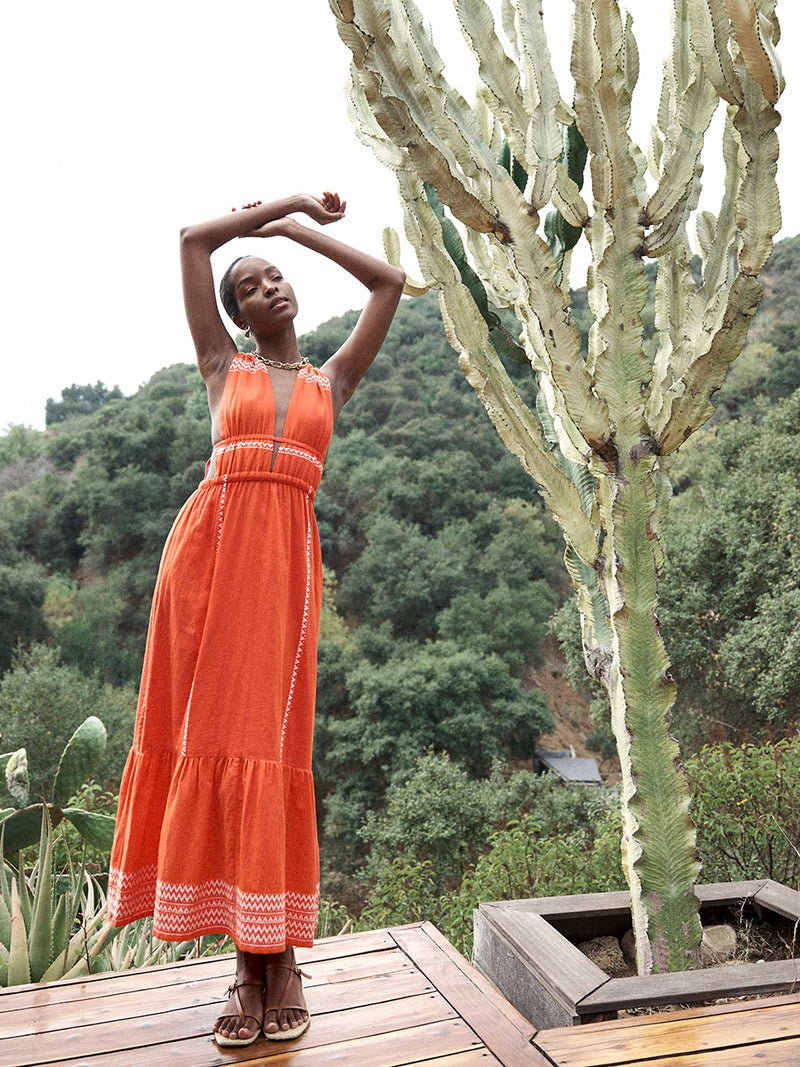 Woman Standing in the tree house Wearing lemlem LELISA Dress featuring an intricate Tibeb pattern in rich red and vanilla colors