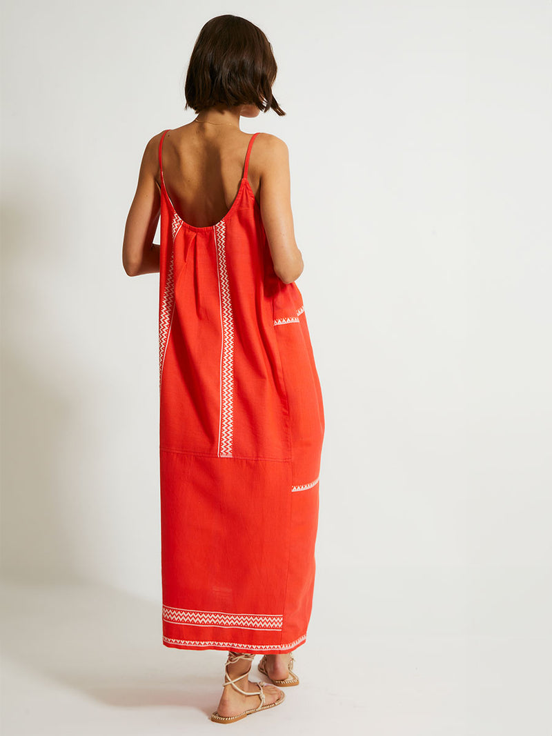 Back of a Woman Standing Wearing lemlem NIA Dress featuring an intricate Tibeb pattern in rich red and vanilla colors