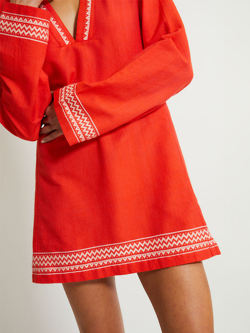 Close up on a Woman Standing Wearing lemlem Raey Dress featuring an intricate Tibeb pattern in rich red and vanilla colors