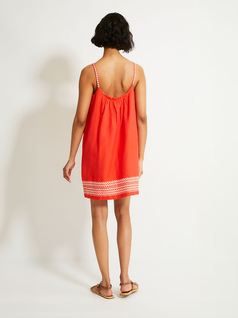 Back of a Woman Standing Wearing lemlem ZINA Dress featuring an intricate Tibeb pattern in rich red and vanilla colors