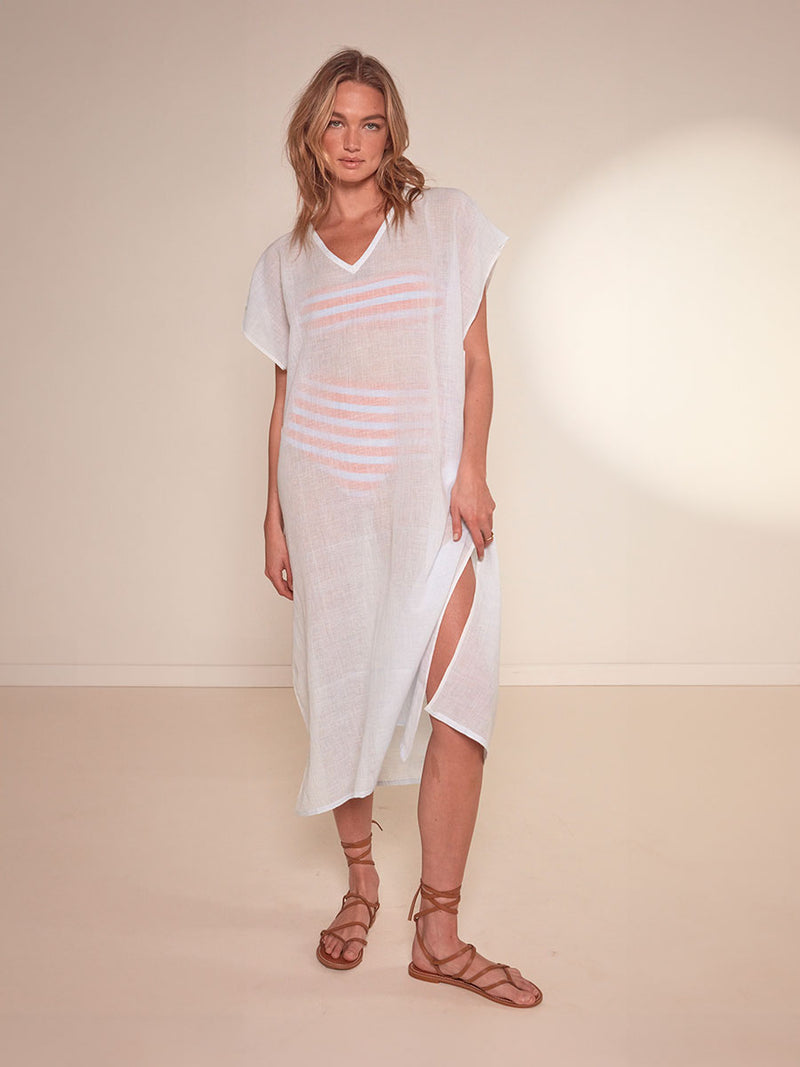 Woman Standing Wearing lemlem Dalila V Neck Caftan featuring airy gauze fabric in a delicate pale blue color, jeliba tangerine bandeau top and high waist bottom