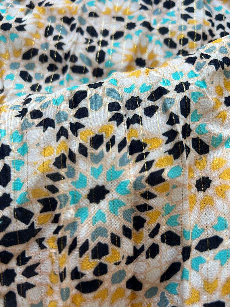 close up on lemlem telem honey fabric featuring  prints inspired by the richly colored ceramic tiles of North Africa, in shades of honey, dark blue, pale blue, and navy blue. 