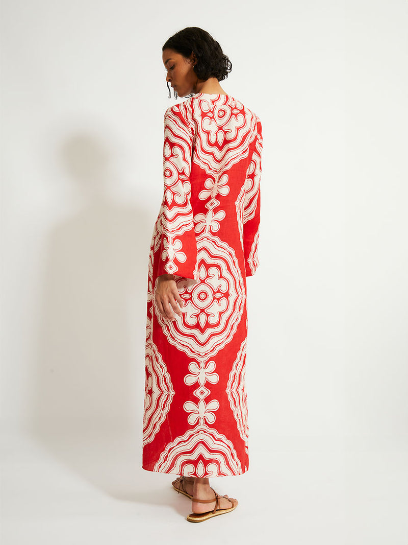 Back of a Woman Standing Wearing lemlem Theodora Dress featuring custom-designed print inspired by ancient architectural patterns in rich, vibrant red and creamy ivory colors.