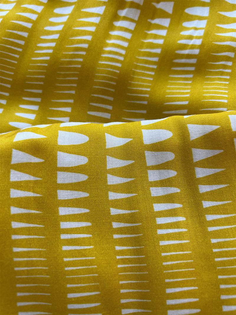 close up on lemlem welele yellow fabric featuring vibrant yellow base adorned with a striking white Tibeb pattern