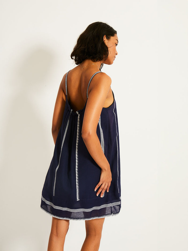 Back of a Woman standing wearing a navy with white stripes and graphics swing dress