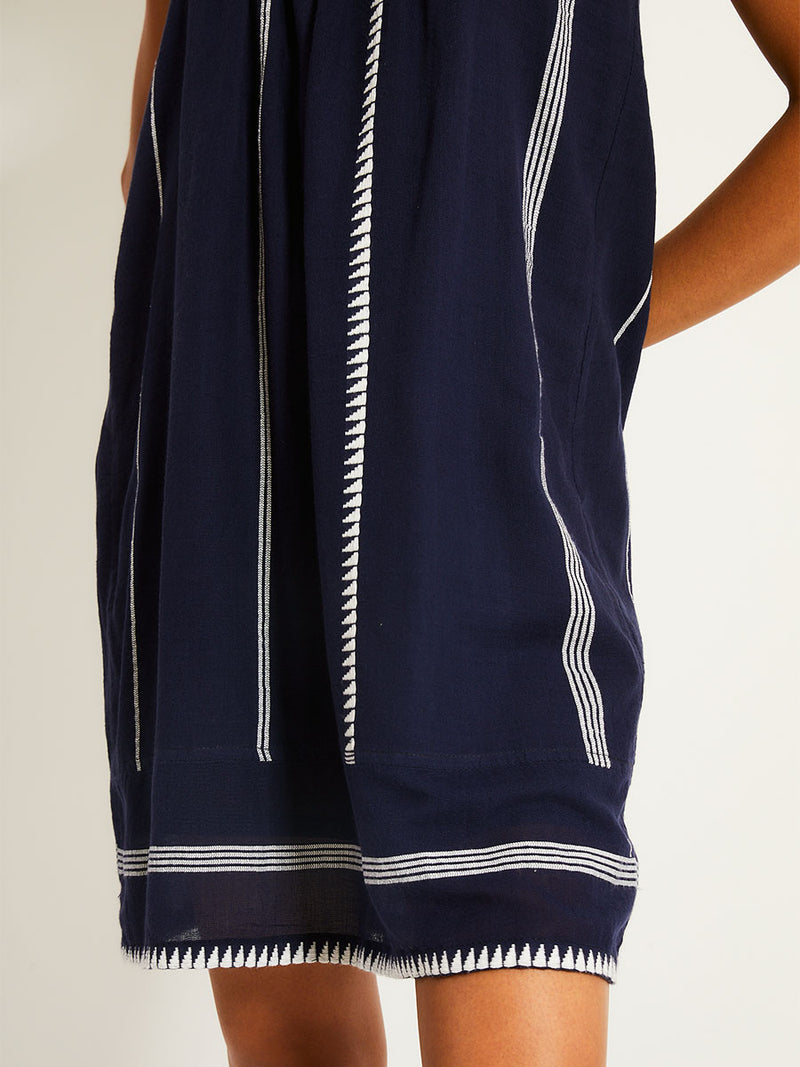 Close up on a Woman standing wearing a navy with white stripes and graphics swing dress